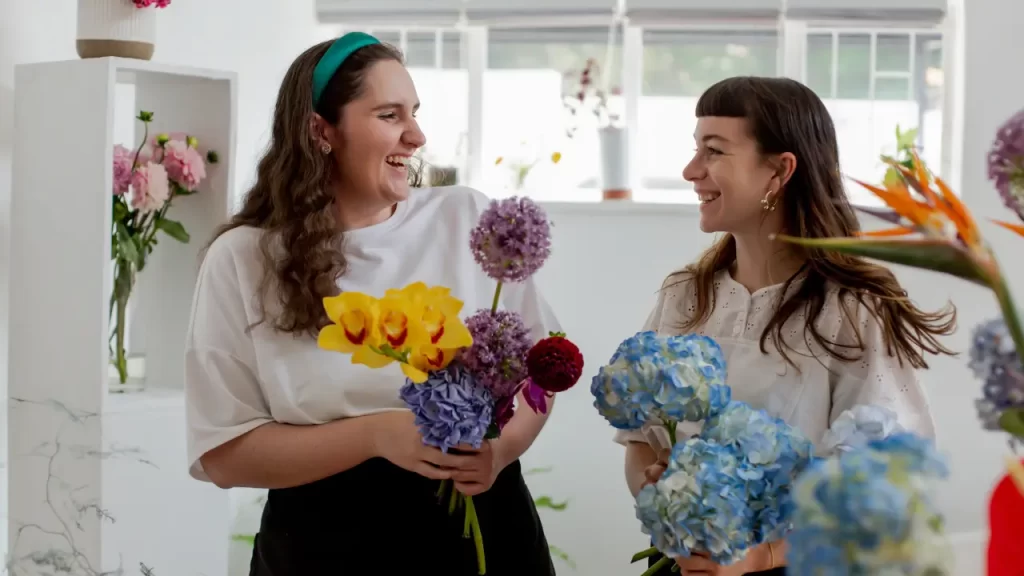 duas mulheres sorrindo com flores diferentes nas mãos
